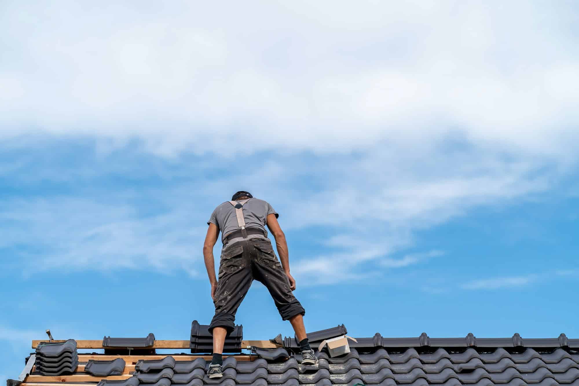 workman on the roof of a family house building a roof covering from ceramic tiles
